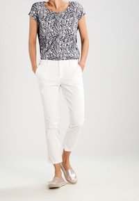 Top de manga corta de rayas en azul marino y blanco, pantalones ajustados blancos y zapatos metálicos de lona. Conjunto casual con un ajuste relajado.