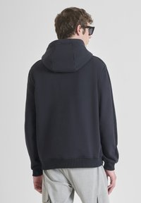 Hoodie grigio scuro con un ampio cappuccio, polsini e orlo a coste. Il tessuto appare morbido con una texture liscia, visto da dietro.