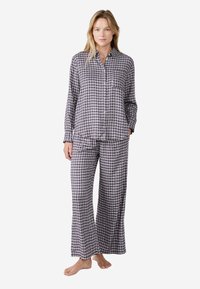 Lang plaid pyjama set bestaande uit een knoopdoorhaalshirt en wijde broek in marineblauw, wit en bordeauxrood, gemaakt van zachte katoen.