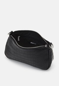 Zwarte nep krokodillenleren clutch met zilveren rits, binnenzak met rits en label "ginatricot" aan de binnenkant.