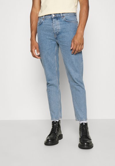 Hellblaue Jeans aus Denim mit geradem Schnitt, fünf Taschen und einer distressed Optik. Kombiniert mit schwarzen geschnürten Stiefeln.