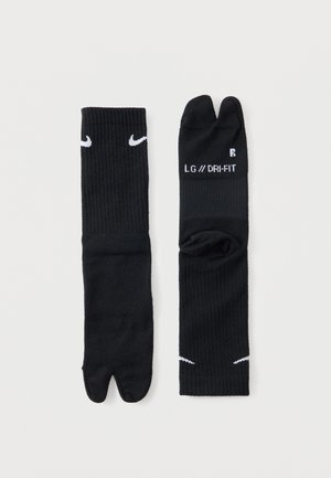 Pari mustia Nike tabi -väriset erottelevat varvassukat, joissa on valkoiset swoosh-logot ja "LG // DRI-FIT"-teksti yhdellä sukat.