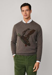 Maglione grigio a maglia con un design di anatra volante multicolore. Collo rotondo, maniche lunghe e polsini a costine; abbinato a pantaloni in velluto a coste verdi.
