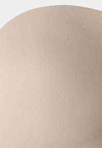 Beige naadloze stof met een geribbelde textuur, gladde afwerking en ronde vorm, geschikt voor strakke kleding of onderkleding.
