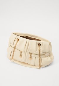 Μπεζ τσάντα με πτυχωτό σχέδιο, δύο μπροστινές τσέπες με φερμουάρ, χρυσές λεπτομέρειες και λουριά με αλυσίδα. Μαλακό υλικό με υφή.