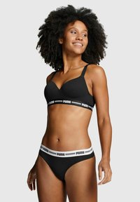 Schwarzes Lingerie-Set mit gepolstertem BH, verstellbaren Trägern und elastischem Bund, verziert mit weißen Markenlogo-Details.