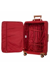 Valigia rossa con guscio rigido, manico retrattile marrone e quattro ruote. L'interno presenta un scomparto con zip e cinturini regolabili.