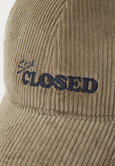 Cappello in corduroy color marrone con superficie testurizzata e la scritta "CLOSED" ricamata in blu scuro. Il design presenta motivi a righe verticali.