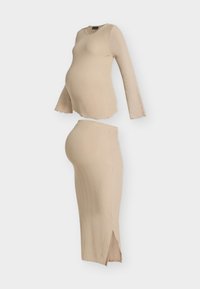 Conjunto beige de maternidad de canalé con blusa de manga larga y falda ajustada con una abertura lateral, presentado sobre un fondo blanco.