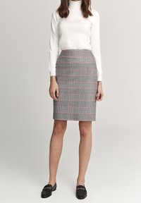 Grå rutiga kjol med rosa accenter, knälång, figurnära design. Matchas med en vit polotröja och svarta loafers för en välvårdad look.