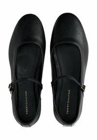 Czarne skórzane baleriny Mary Jane z cienkimi regulowanymi paskami i złotymi klamrami, z markowymi wkładkami oznaczonymi nazwiskiem Tommy Hilfiger.