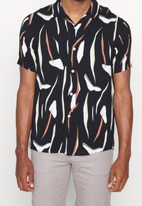 Korte mouwen overhemd in zwart met abstracte, multicolor patronen. Voorzien van een knoopsluiting aan de voorkant en een zachte stoftextuur.