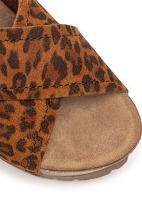 Brown suede sandal with a leopard print pattern, cross-strap design, and a textured sole. Features a soft, padded footbed for comfort.