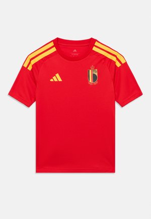 Camiseta deportiva roja con rayas amarillas de Adidas en los hombros, logo de Adidas en el pecho derecho y emblema de la Real Asociación Belga de Fútbol en el pecho izquierdo.