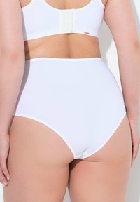 Culotte blanche taille haute avec une texture lisse et une ceinture élastique contrastante, dotée d'une fermeture à crochet et œillet à l'arrière.