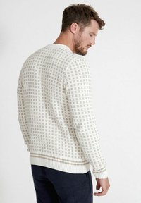 Gehaakte trui in crème met een ruitpatroon en geribde manchetten. Ronde halslijn en een relaxed fit, met textuurdetails overal.