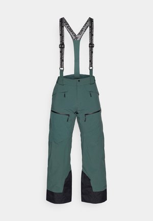 Zelene smučarske hlače s črnimi detajli, nastavljivi črni naramnice, več žepov z zadrgo in ohlapen kroj za gibljivost.