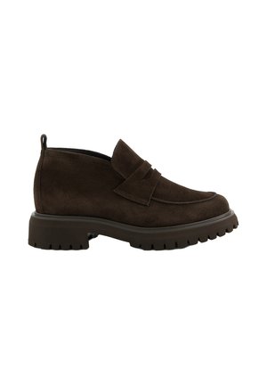 Mocassin en daim marron foncé avec une semelle crantée épaisse et un petit talon, présentant une bride décorative sur le cou-de-pied et une languette à l’arrière.