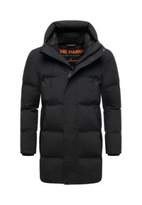 Melna pūkainā jaka ar kapuci, ar rāvējslēdzēju un spiedpogām. Materiāls ir gluds ar redzamām izšūtām sekcijām.