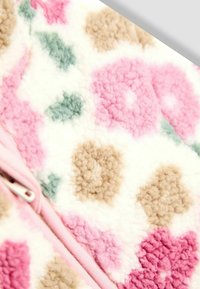 Tejido de forro polar con un patrón floral en tonos de rosa, verde y marrón sobre un fondo blanco, con un cierre de cremallera rosa pálido a lo largo del borde.