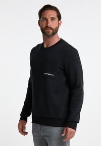 Felpa nera in misto cotone, con polsini e orlo a coste, tasca sul petto e logo "TUFFSKULL" in bianco.