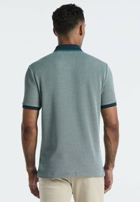 Korte mouw polo-shirt in lichtgroene textuur met een marineblauwe kraag en mouwafwerkingen, voorzien van een rechte zoom en subtiel patroon.