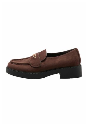 Ruskea mokkanahkainen loafer mustalla paksulla korolla ja kultaisen sävyisellä metallikoristeella remmissä, sivukuva valkoisella taustalla.