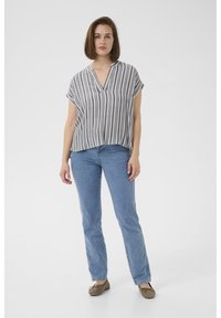 Camicia a maniche corte a righe grigia e bianca, design a V. Abbinata a jeans a gamba dritta azzurri chiari e scarpe flat marroni.