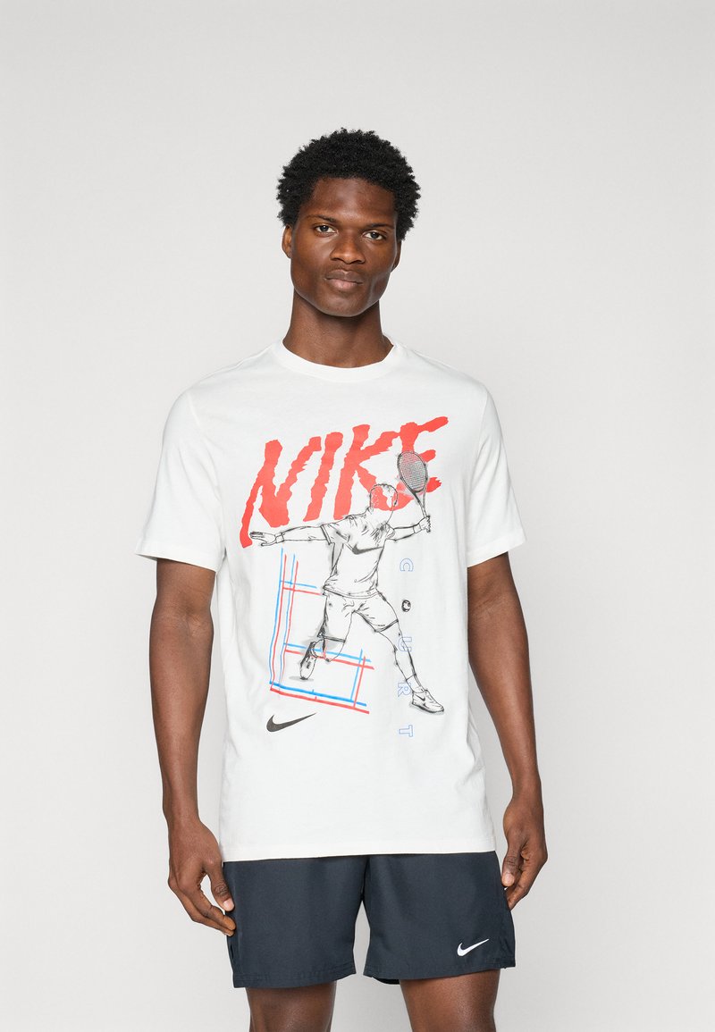 Balta kokvilnas T-kreklā ir liels sarkans "NIKE" grafiks, spēlētāja ar raketi zīmējums un zila režģa dizaina detaļas. Melni šorti un logotipa elements.