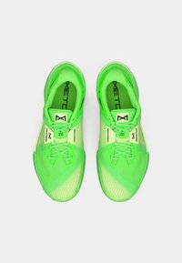 Zöld sportcipők texturált hálós felsőrésszel, lapos fűzőkkel és logós részletekkel. Az elegáns dizájn kontrasztos zöld árnyalatokkal rendelkezik.