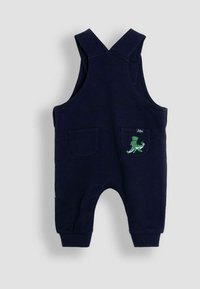 Tumši zils kombinezons, kas izgatavots no kokvilnas, ar regulējamiem siksniņām, divām priekšējām kabatām un zaļu dinozauru izšuvumu uz labās kabatas.