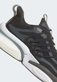 Baskets de sport noires avec une tige en mesh texturé, semelle blanche et bleu glace, six lacets et accents en caoutchouc. Dispose d'une languette de traction arrière bien visible.
