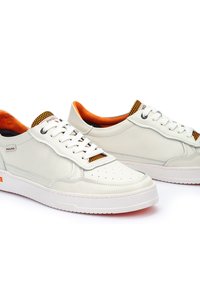 Zapatillas de piel blanca con detalles en naranja y acentos de malla, que cuentan con punteras perforadas, cordones planos y una suela de goma sólida.