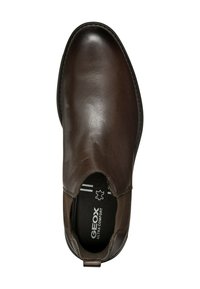 Zapato de cuero marrón con punta redondeada y paneles laterales elásticos. Presenta una superficie texturizada y una plantilla de soporte etiquetada como "GEOX Ultra Comfort."