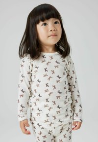 Ensemble de pyjama en coton blanc comprenant un haut à manches longues et un pantalon, orné d'un motif répétitif de petits nœuds marron et noir.