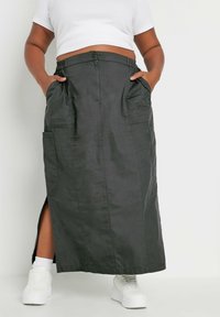 Mustapitu maxi-hame, jossa on nappi ja joustavyötärö, sivutaskut ja reiden yli ulottuva halkio. Yhdistetty valkoiseen crop-toppiin ja valkoisiin lenkkareihin.