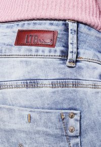 Vaaleansiniset farkut, joissa on ruskea LTB-nahkaleima vyötäröllä. Farkuissa on klassinen taskusuunnittelu ja hienovaraiset tekstuurimuutokset.