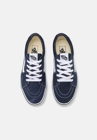 Baskets en daim bleu marine avec lacets blancs, présentant un design classique, une semelle en caoutchouc, des détails de couture et le logo Vans sur la languette.