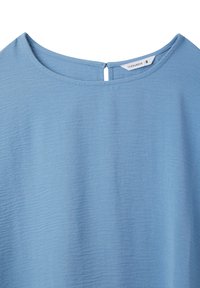 Top blu chiaro realizzato in tessuto testurizzato; scollatura rotonda con un piccolo dettaglio a forma di chiave sul retro; design senza maniche.