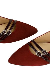 Scarpe rosse in suede con punta a punta, dotate di due cinturini lucidi in vernice marrone con fibbie circolari in argento. La fodera interna è in pelle beige.