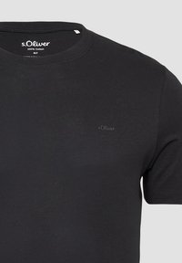 Zwart T-shirt met korte mouwen, gemaakt van 100% katoen, met een ronde hals en een subtiele s.Oliver-logo op de borst. Zachte textuur, klassieke pasvorm.