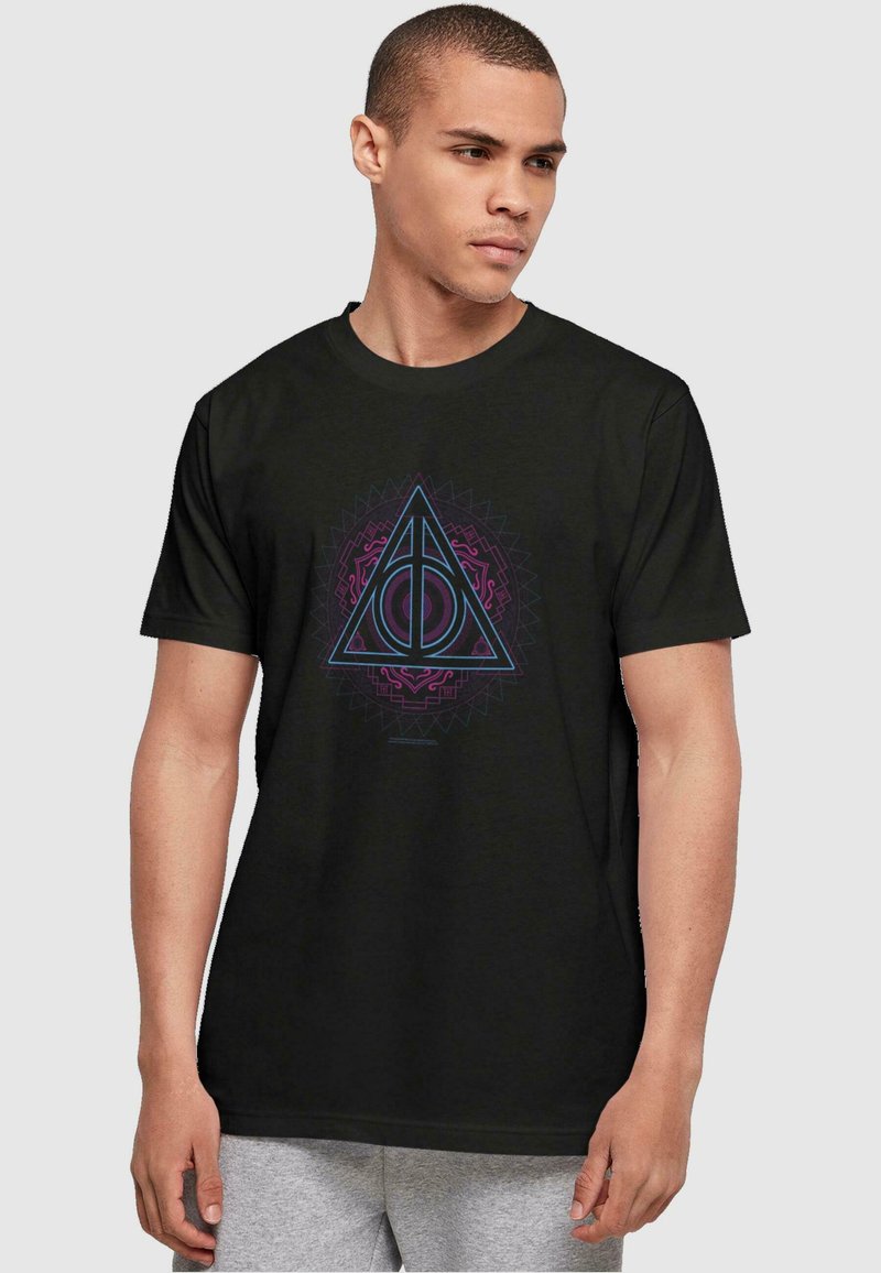 Camiseta de manga corta negra con un diseño geométrico triangular que presenta acentos en púrpura y azul, centrado en el pecho sobre un fondo sólido.