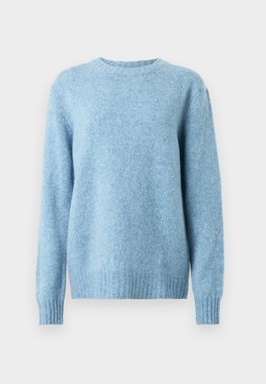 Lys blå strikkegenser med rund hals, lange ermer og ribbestrikkede mansjetter og nederkant. Materialet ser mykt og litt strukturert ut.