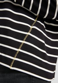 Schwarz-weiß gestreifter Pullover mit strukturiertem Strick. Verfügt über kontrastierende gelbe Nähte entlang der Seitennähte und des Saums.