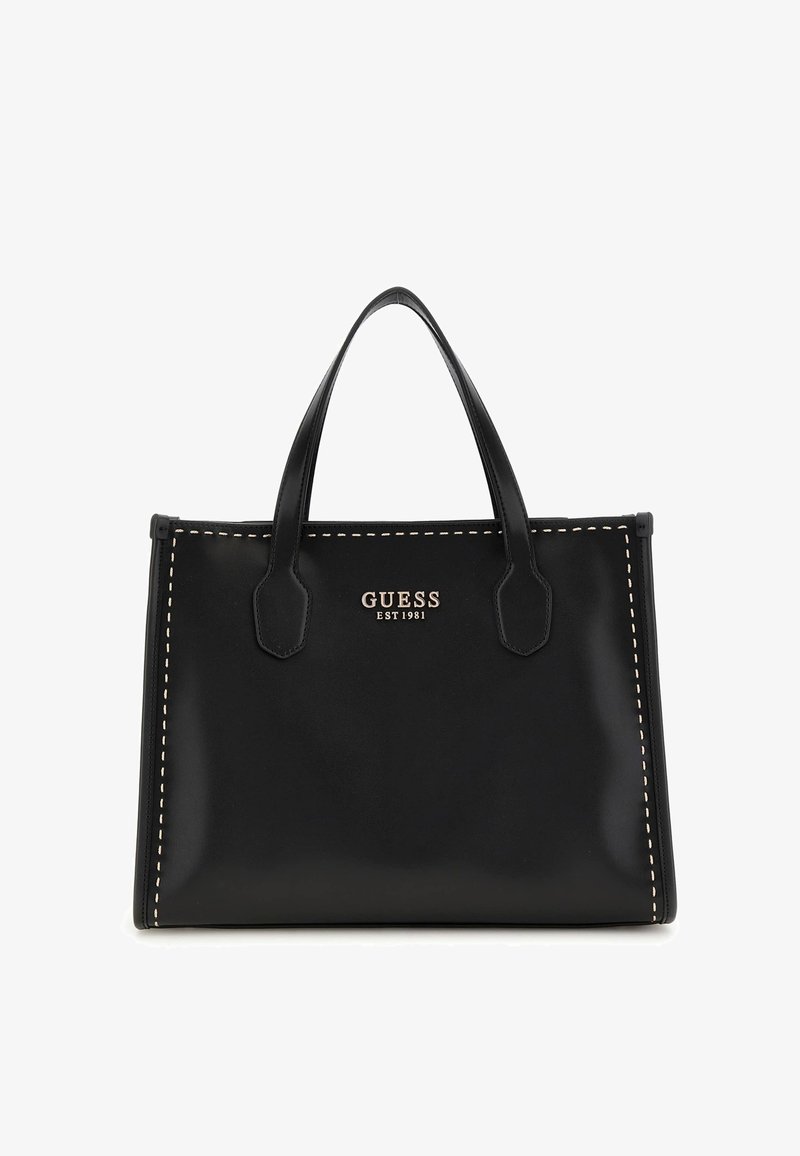 Sac à main en cuir noir avec des coutures contrastées, forme structurée, deux poignées et un emblème doré portant l'inscription "GUESS EST 1981".