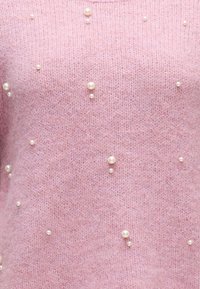 Tissu en maille rose doux orné de petites et moyennes perles blanches dispersées en grappes et placements individuels.