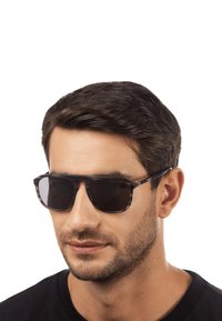 Occhiali da sole neri con una forma rettangolare elegante e lenti scure, caratterizzati da una montatura sottile e un design minimalista.