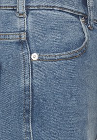 Blauwe denim jeans met een traditionele vijf-pocket ontwerping, zichtbare stiksels en een metalen knopen sluiting op de voorkomp.