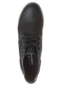 Chaussure en cuir noir avec un bout arrondi, design à lacets, surface texturée et couture blanche contrastante. L'intérieur présente l'étiquette de la marque.