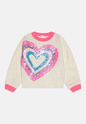 Dziecięcy sweter z kremowej dzianiny z jasnoróżowym obszyciem i wielokolorowym sercem z cekinów na przodzie.